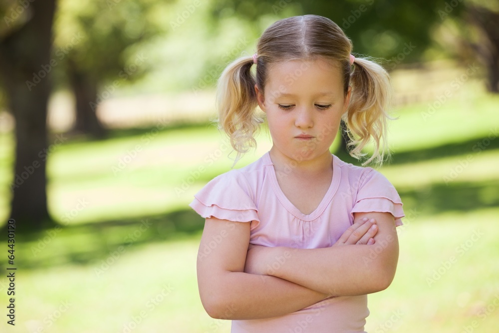 Sad young girl with arms crossed at park Sad young girl with arms crossed at park
