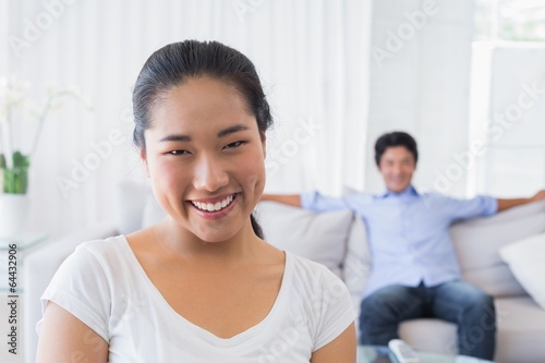 Happy woman smiling at camera with boyfriend in back