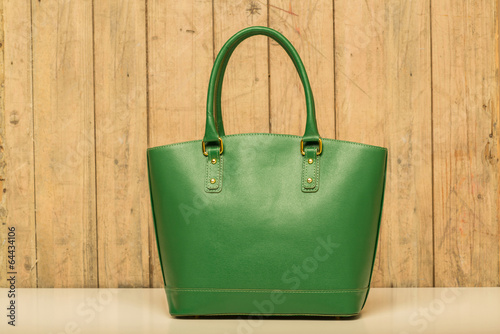 green purse on wood background