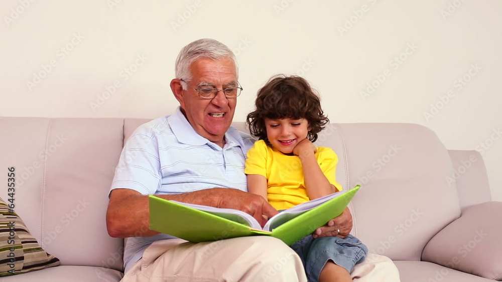 Senior man sitting on couch with his grandson looking at photo a Senior man sitting on couch with his grandson looking at photo a