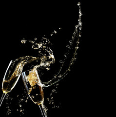 Glasses of champagne with splash, on black background