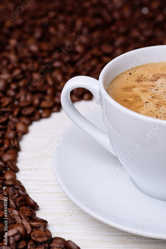 white cup of coffee on a background of coffee beans