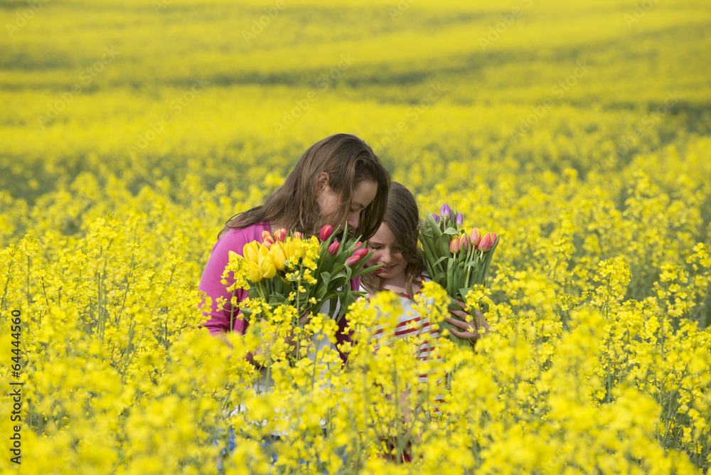 Girls holding Spring flowers in rapeseed field Girls holding Spring flowers in rapeseed field