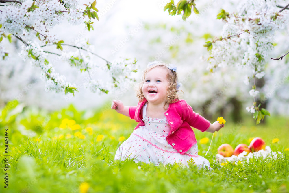 Beautiful toddler girl eating apple in blooming garden Beautiful toddler girl eating apple in blooming garden