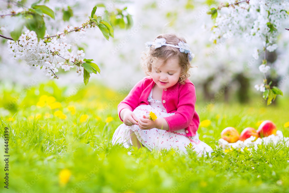 Sweet little girl eating apple in a spring blooming garden Sweet little girl eating apple in a spring blooming garden