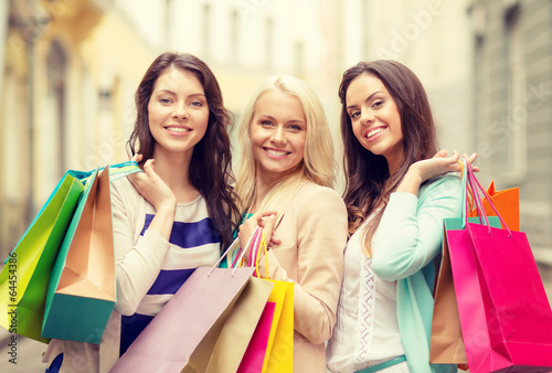 three smiling girls with shopping bags in ctiy