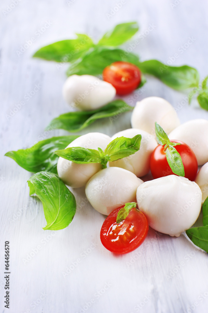 Tasty mozzarella cheese with basil and tomatoes, on wooden Tasty mozzarella cheese with basil and tomatoes, on wooden