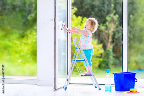 Little girl washing a window with view garden © famveldman