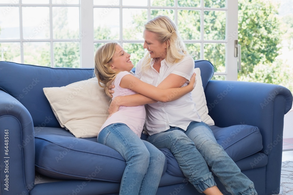 Mother and daughter embracing on sofa