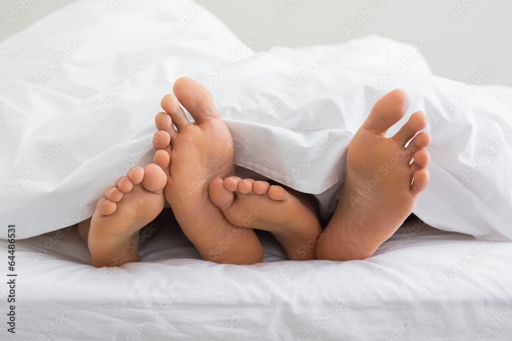 Couples feet sticking out from under duvet Couples feet sticking out from under duvet
