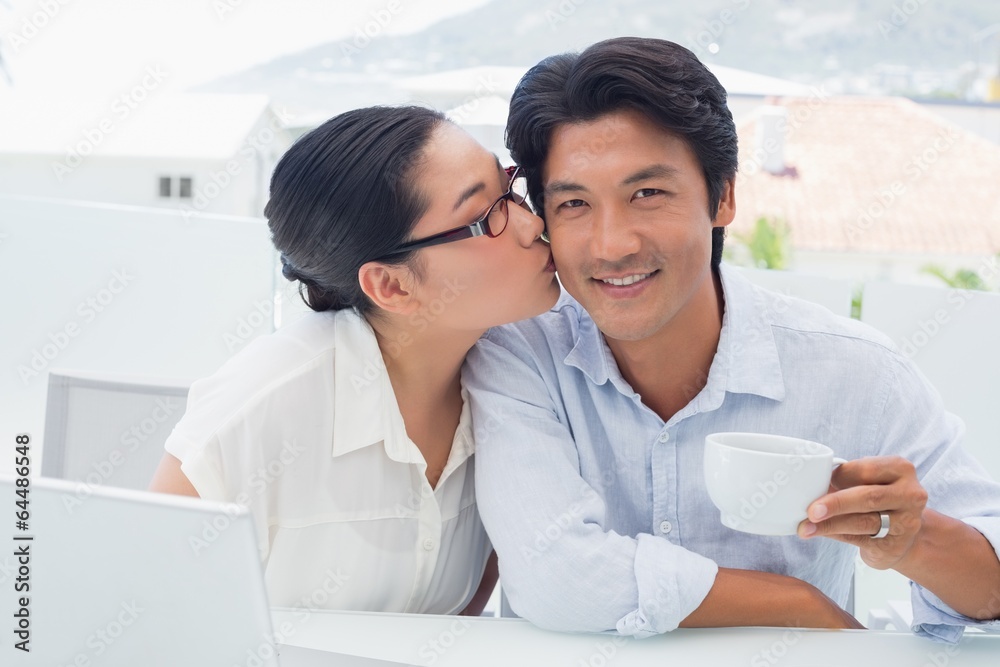 Woman kissing her boyfriend on the cheek having coffee Woman kissing her boyfriend on the cheek having coffee