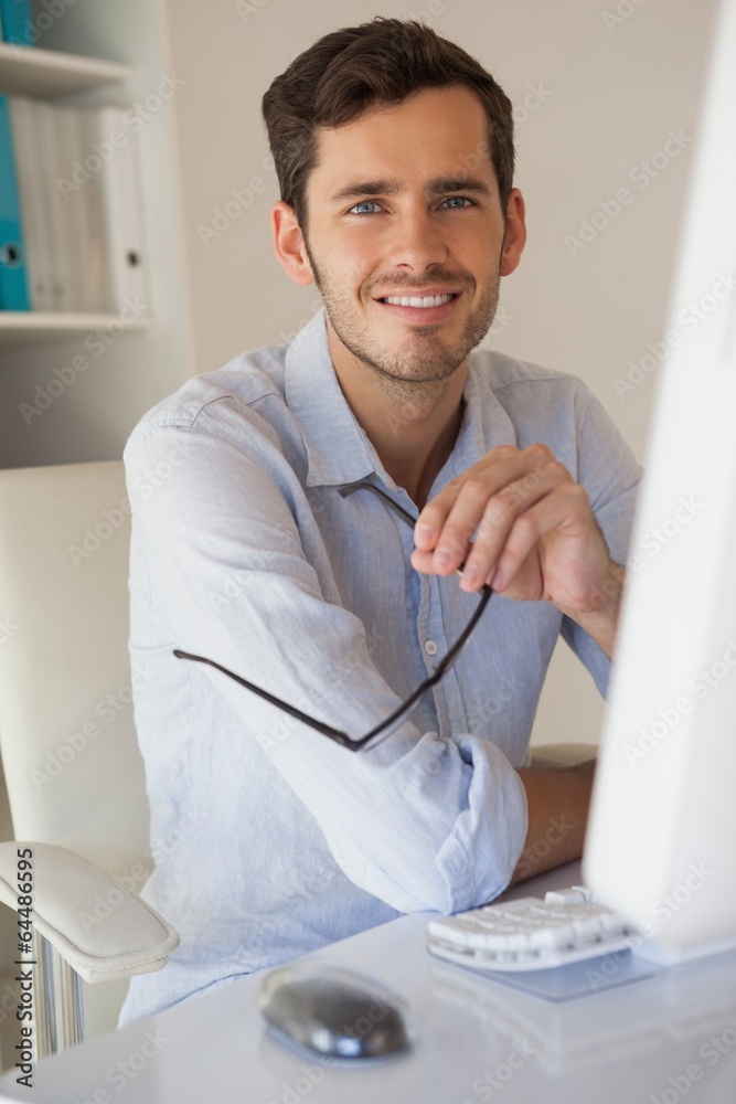 Fototapeta premium Casual businessman smiling at camera at his desk