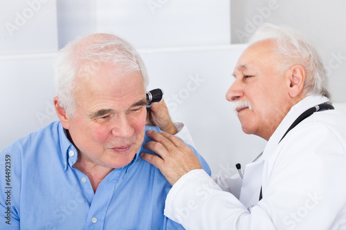 Doctor Examining Senior Man's Ear With Otoscope