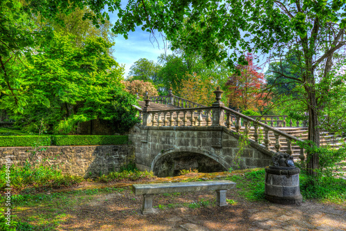 A painting alike picture of a small bridge over water with trees