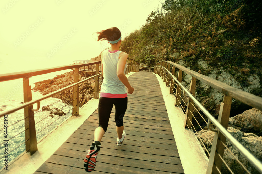 Obraz premium fitness woman running at seaside wooden bridge