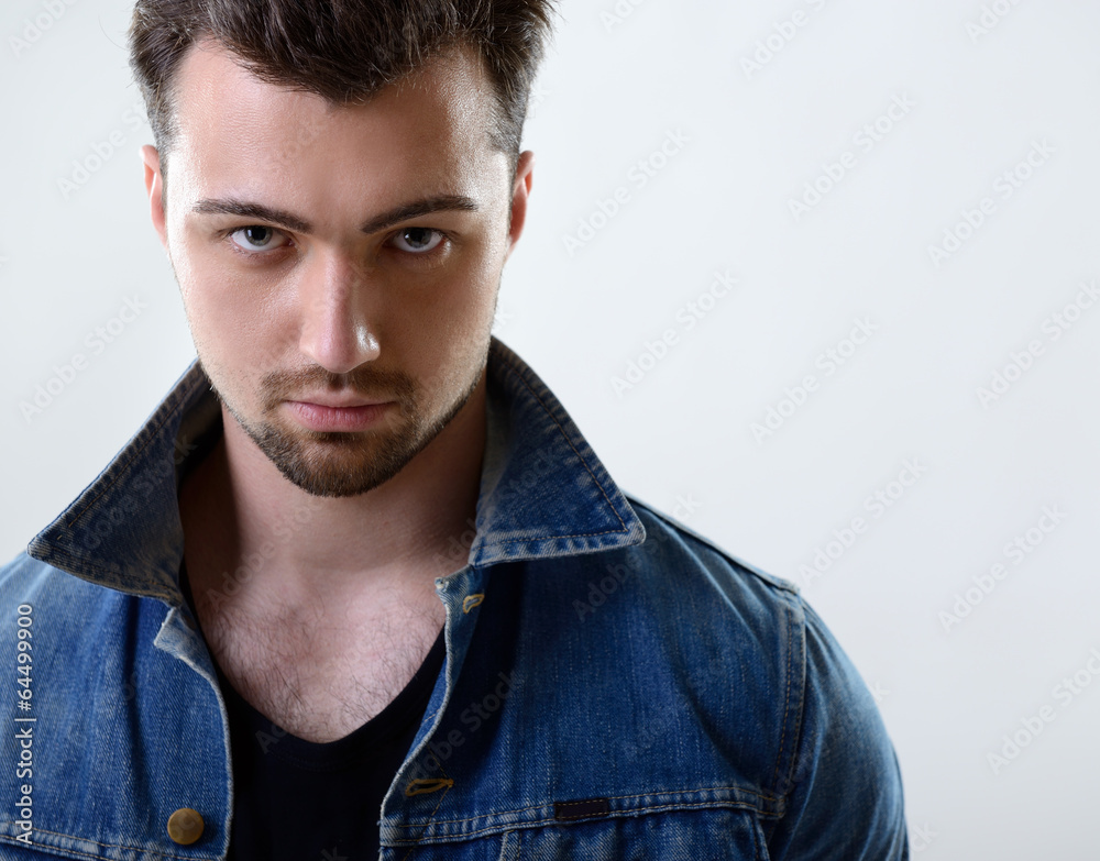 Obraz premium Portrait of handsome young man in jeans jacket, on gray backgrou