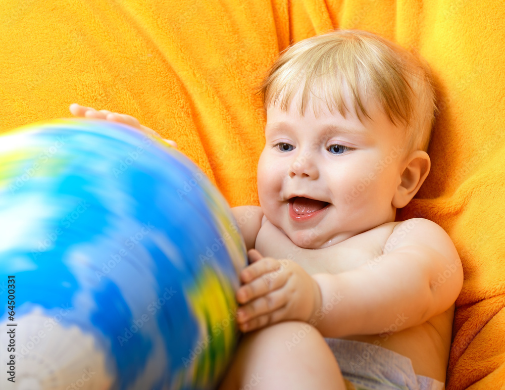 Happy baby playing with terrestrial globe on an orange plaid Happy baby playing with terrestrial globe on an orange plaid