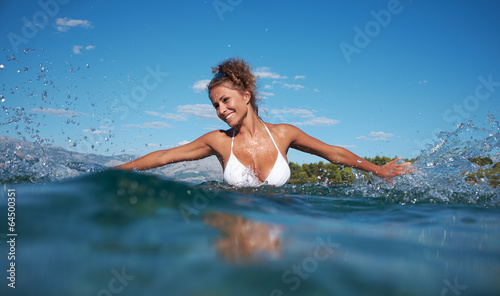 Beautiful young woman in bikini on the beach splashing water © ZoomTeam