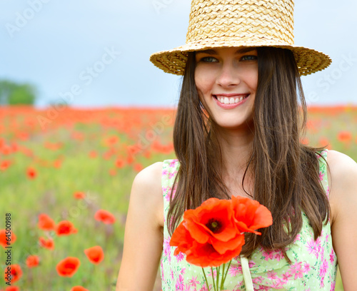 Young beautiful happy woman in straw hat on a poppy field, summe photo