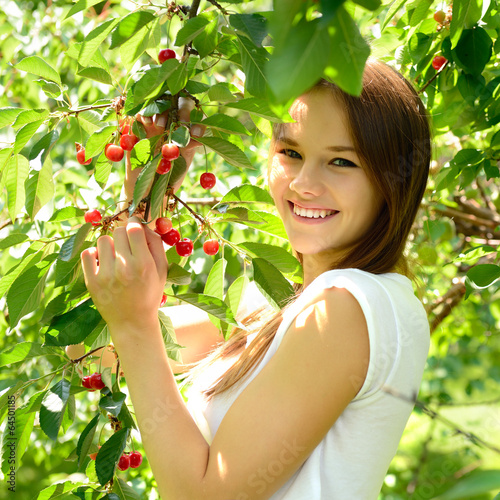 portrait of pretty cheerful young girl in cherry garden