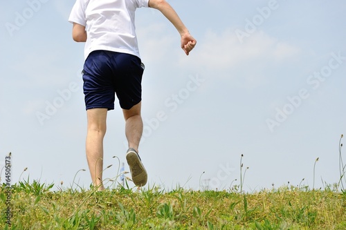 緑の草原の上を走るスポーツウェアの男性