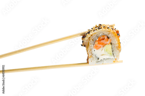 Isolated sushi roll in chopsticks. Macro.