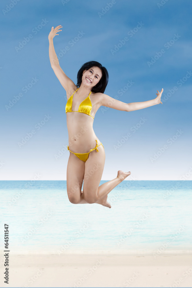 Attractive woman in bikini jumping at beach 1 Attractive woman in bikini jumping at beach 1