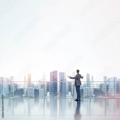 Business man standing on a roof and looking at city