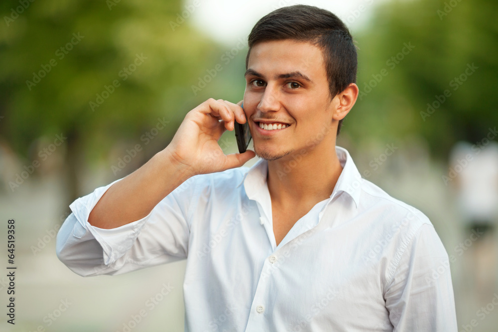 Young man standing outdoors, talking on the phone. Young man standing outdoors, talking on the phone.