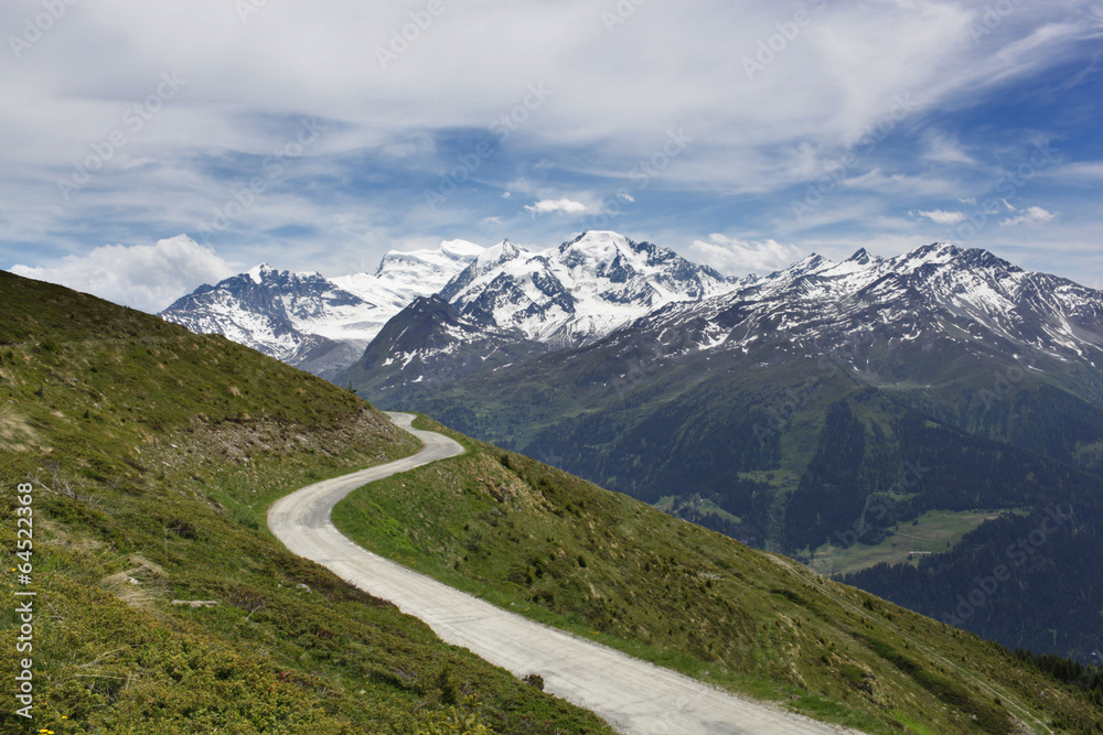 A mountain road winding towards spectacular mountains