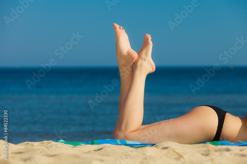 Summer vacation. Legs of sunbathing girl on beach