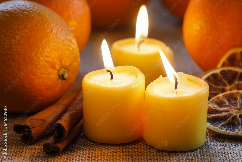 Beautiful candles and juicy oranges on jute table cloth Beautiful candles and juicy oranges on jute table cloth