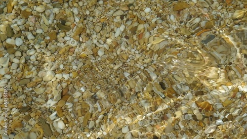 Close up of very calm sea surf splashing on a pebble beach