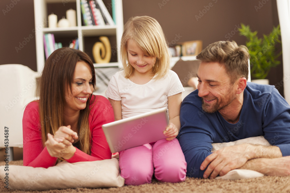 Loving family using digital tablet on carpet Loving family using digital tablet on carpet