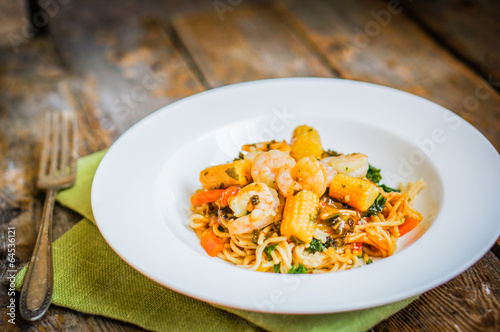 Italian pasta with shrimps and vegetables on wooden background