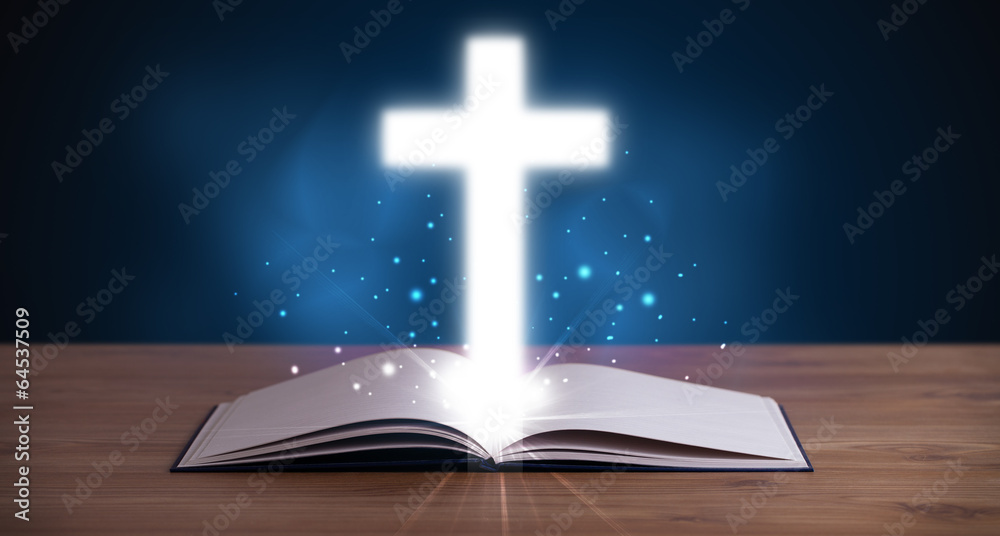 Open holy bible with glowing cross in the middle