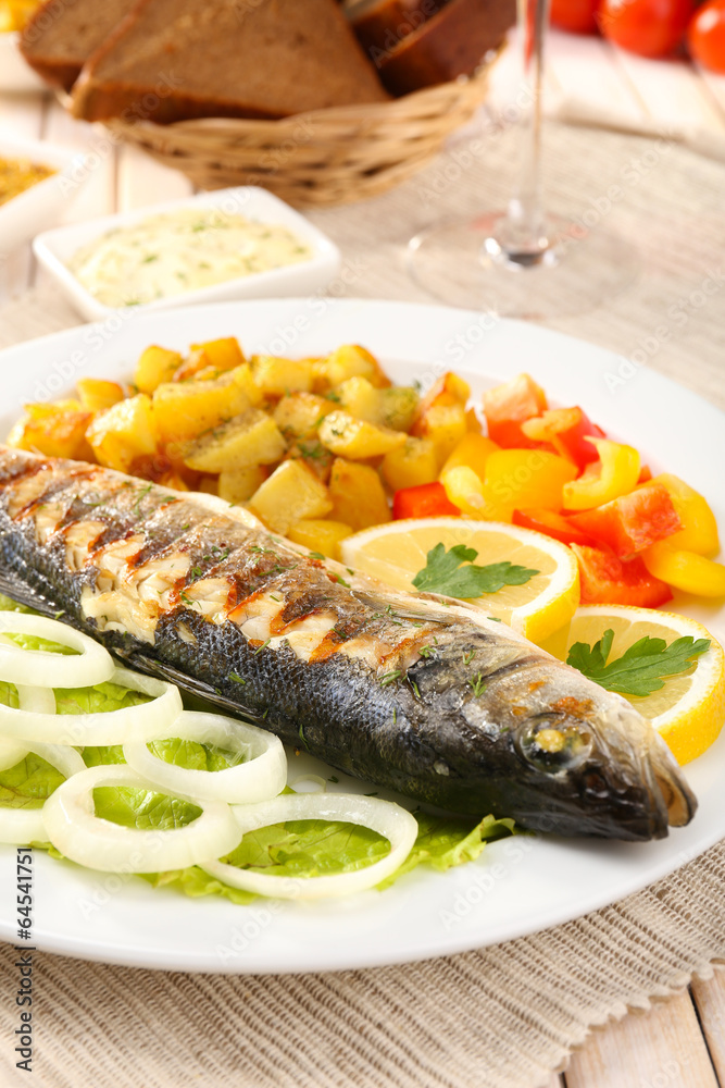 Delicious grilled fish on plate on table close-up Delicious grilled fish on plate on table close-up