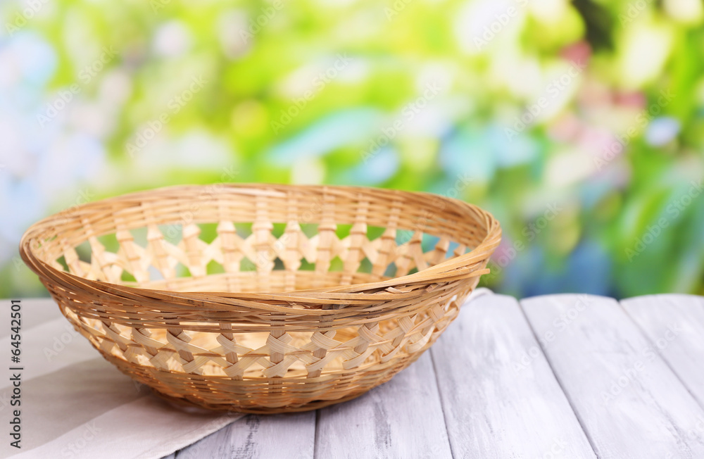 Empty wicker basket on wooden table, on bright background Empty wicker basket on wooden table, on bright background