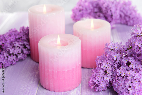Beautiful lilac flowers with candles on table close-up