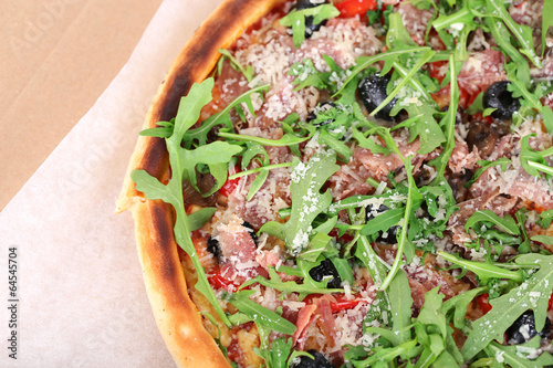 Pizza with arugula, in pape rbox, close-up photo