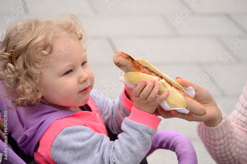 girl takes a white bun with sausage