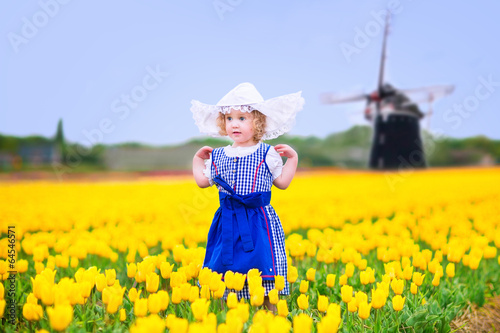Photography Beautiful girl in Dutch costume in tulips field next windmill