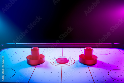 Dramatic lit air hockey table with puck and paddles photo