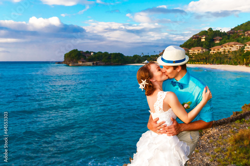 Wedding. Bbride and groom kissing on the tropical coast at sunse photo