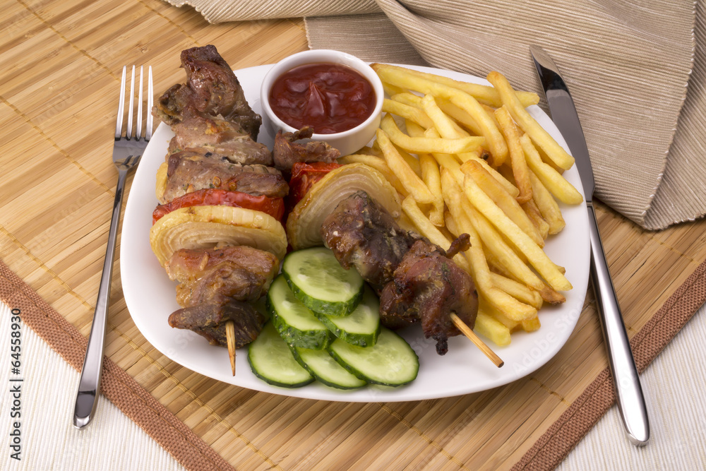 Kebab and fries, sauce, cucumber and fork knife Kebab and fries, sauce, cucumber and fork knife