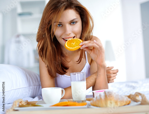 woman eating healthy fruit in bed while happy and smiling