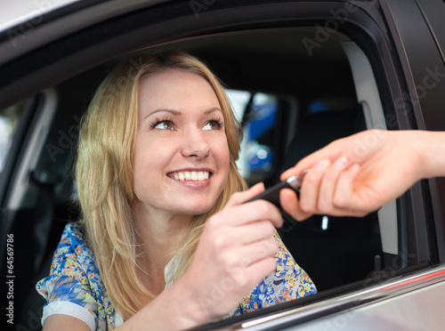 Happy smiling woman with car key in car.