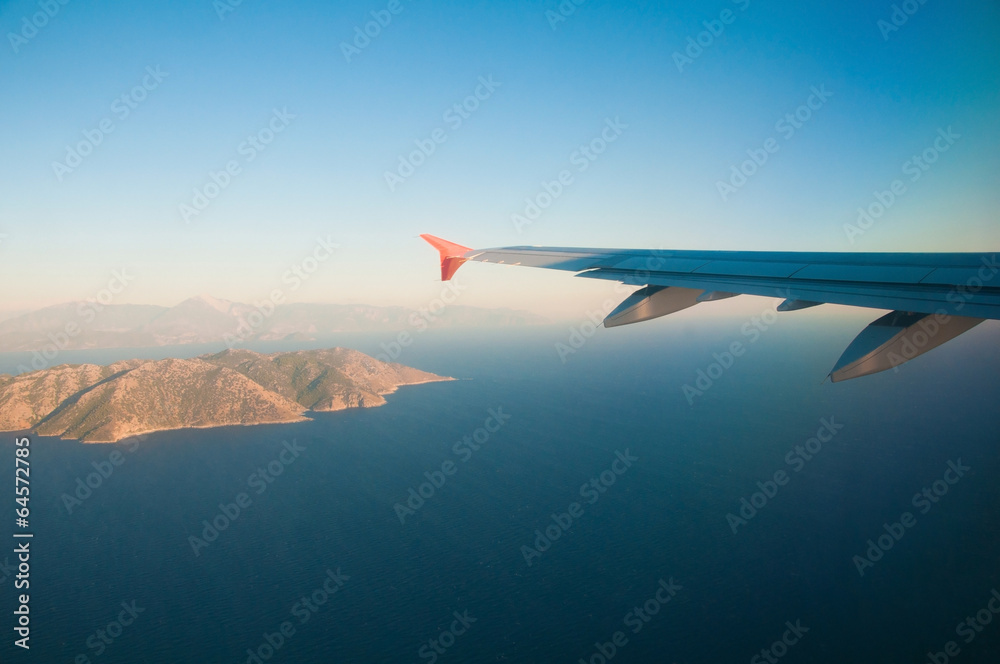 View from the airplane over the sea, the mountains, the wing