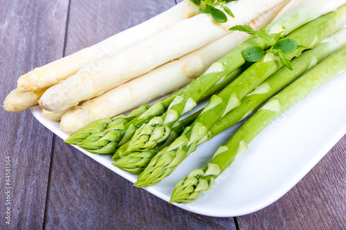 ungeschälter Spargel auf Platte mit Kräutern