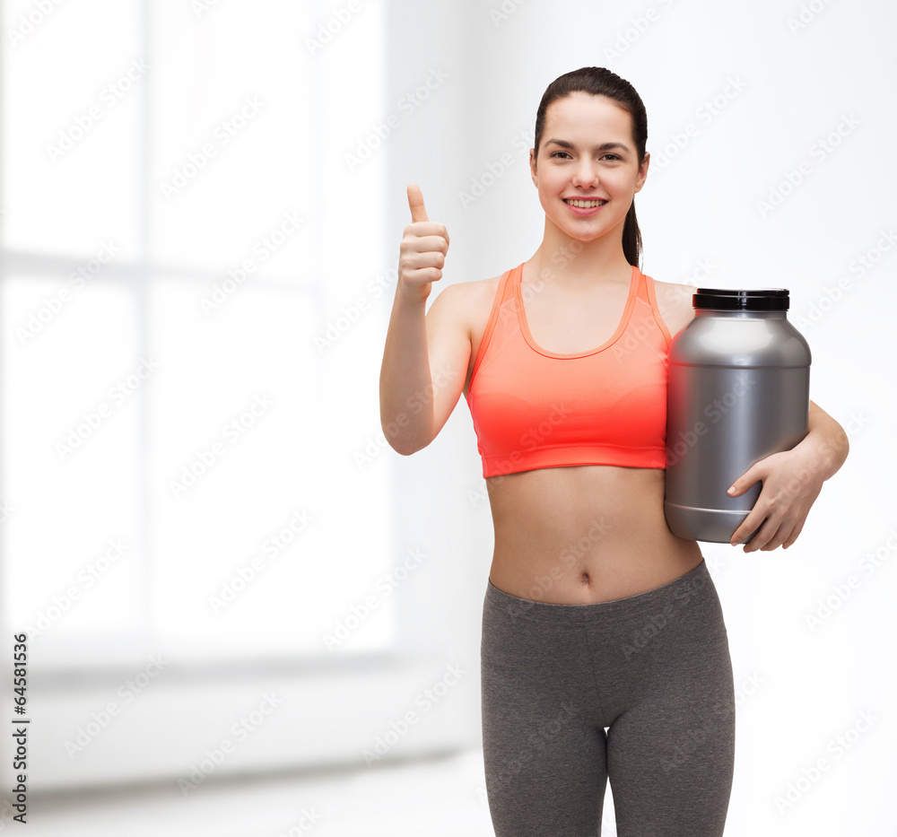 teenage girl with jar of protein showing thumbs up teenage girl with jar of protein showing thumbs up